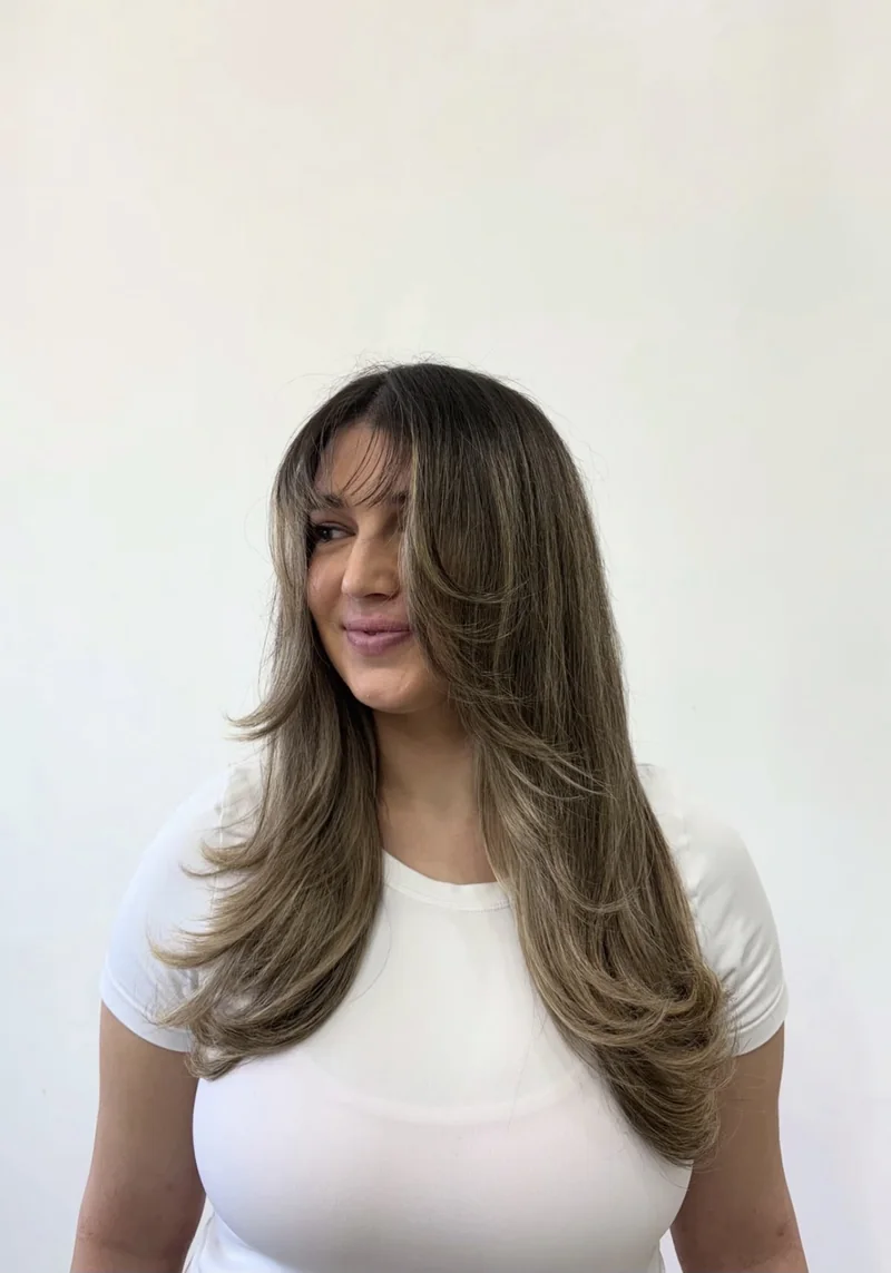 A long layered blowout with face-framing fringe and soft highlighted ends.